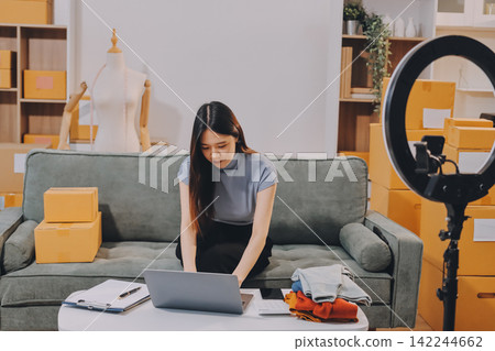 Woman recording live stream preparing packages for online selling 142244662