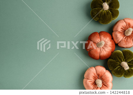 Autumnal harvest decorations featuring plush pumpkins in seasonal orange and green velvet fabrics arranged artistically Autumnal harvest decorations featuring plush pumpkins in seasonal orange and green velvet fabrics arranged artistically 142244818