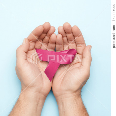 Male hands holding a pink ribbon, symbol of breast cancer awareness Male hands holding a pink ribbon, symbol of breast cancer awareness 142245000