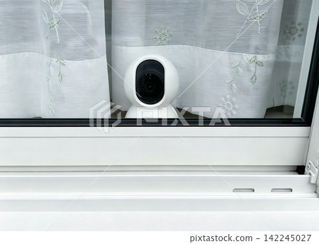A freestanding, rotating security camera installed on the inside of a window (looking out the window). A freestanding, rotating security camera installed on the inside of a window (looking out the window). 142245027