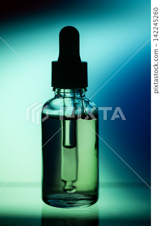 Glass dropper bottle filled with liquid against a gradient blue and green background, showcasing the product's sleek design and transparency Glass dropper bottle filled with liquid against a gradient blue and green background, showcasing the product's sleek design and transparency 142245260