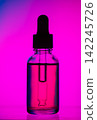 Glass dropper bottle filled with liquid against a vibrant purple and pink gradient background, showcasing the silhouette of the bottle and dropper 142245726