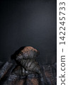 Black croissants stacked on a textured surface with a dark background, showcasing a unique culinary presentation and modern pastry design 142245733