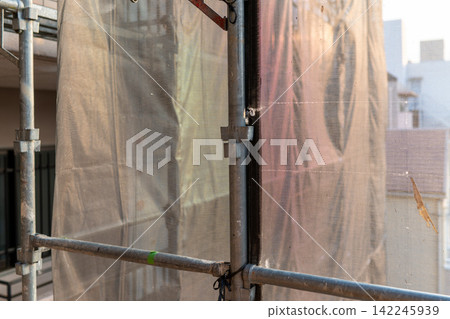 Scaffolding for large-scale apartment building renovation work, illuminated by the twilight. Scaffolding for large-scale apartment building renovation work, illuminated by the twilight. 142245939