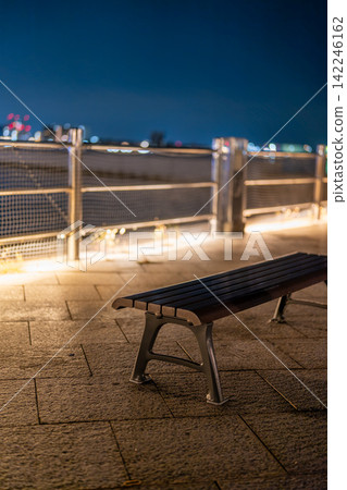 An empty outdoor bench illuminated by warm lighting. An empty outdoor bench illuminated by warm lighting. 142246162