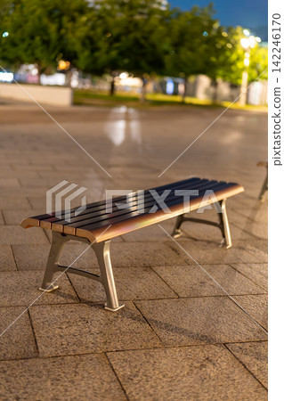 An empty outdoor bench illuminated by warm lighting. An empty outdoor bench illuminated by warm lighting. 142246170