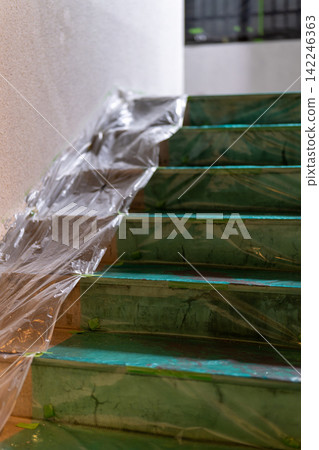 Staircase of a building covered in protective sheeting in preparation for painting work. Staircase of a building covered in protective sheeting in preparation for painting work. 142246363