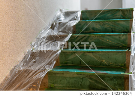 Staircase of a building covered in protective sheeting in preparation for painting work. Staircase of a building covered in protective sheeting in preparation for painting work. 142246364