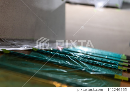 Stairs covered with green protective sheeting and masking tape Stairs covered with green protective sheeting and masking tape 142246365