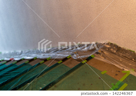 Stairs covered with green protective sheeting and masking tape Stairs covered with green protective sheeting and masking tape 142246367