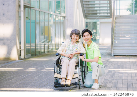 一位坐在輪椅上的老人和一位年輕的男性照護員。 一位坐在輪椅上的老人和一位年輕的男性照護員。 142246976