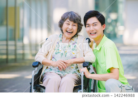 一位坐在輪椅上的老人和一位年輕的男性照護員。 一位坐在輪椅上的老人和一位年輕的男性照護員。 142246988