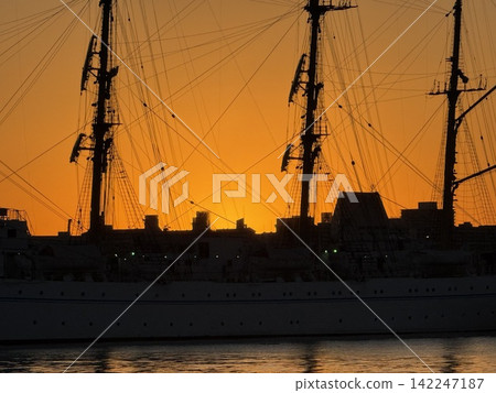 The silhouette of a sailing ship bathed in the orange light of dawn. The silhouette of a sailing ship bathed in the orange light of dawn. 142247187