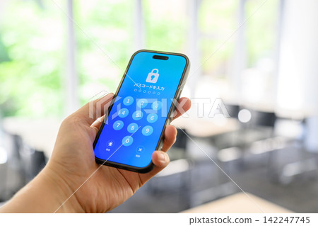 手裡拿著顯示密碼輸入介面的智慧型手機 手裡拿著顯示密碼輸入介面的智慧型手機 142247745