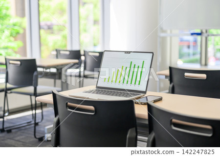教室的桌子上放著一台筆記型電腦和一張圖表。 教室的桌子上放著一台筆記型電腦和一張圖表。 142247825