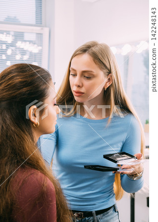Visage routine. Aesthetic makeup. Female professional cosmetologist applying face skin product using tool in studio workspace. Visage routine. Aesthetic makeup. Female professional cosmetologist applying face skin product using tool in studio workspace. 142248143