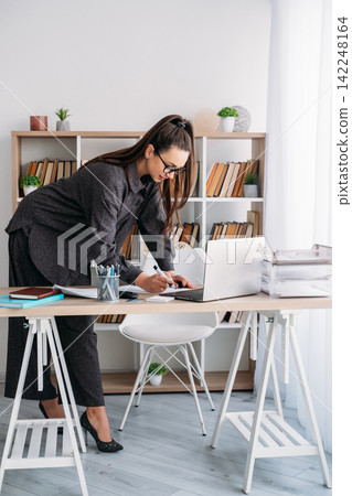 Professional workflow. Office worker. Business woman preparing for occupation at desk with notebook laptop at modern workspace. Professional workflow. Office worker. Business woman preparing for occupation at desk with notebook laptop at modern workspace. 142248164