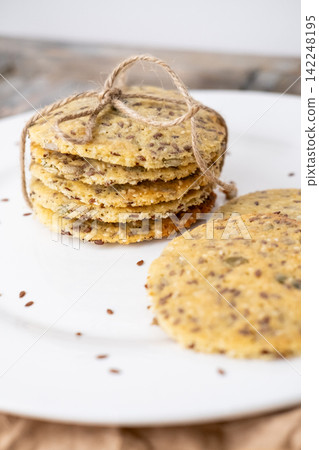 Healthy food. Grain pastry. Round crackers stack tied with jute placed on white ceramic plate. Tasty cookies with flax pumpkin seeds. Healthy food. Grain pastry. Round crackers stack tied with jute placed on white ceramic plate. Tasty cookies with flax pumpkin seeds. 142248195