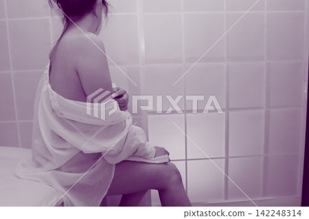 A woman wearing a white shirt sits in a chair. A woman wearing a white shirt sits in a chair. 142248314