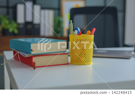 Modern Student Workspace with Stack of Books on White Table. Modern Student Workspace with Stack of Books on White Table. 142248415