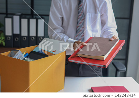Business professional packing up belongings after getting laid off. Business professional packing up belongings after getting laid off. 142248434