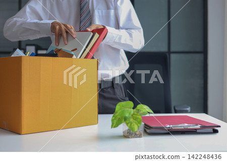 Business professional packing up belongings after getting laid off. Business professional packing up belongings after getting laid off. 142248436