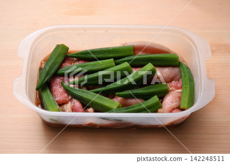 Pork and okra seasoned and placed in a Tupperware container Pork and okra seasoned and placed in a Tupperware container 142248511