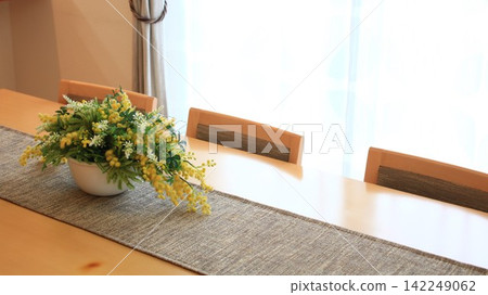 A bright dining table adorned with flowers and a large empty space A bright dining table adorned with flowers and a large empty space 142249062
