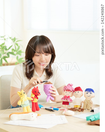 一位女士正在欣賞手工藝品,桌上擺放著一排娃娃。 一位女士正在欣賞手工藝品,桌上擺放著一排娃娃。 142249867