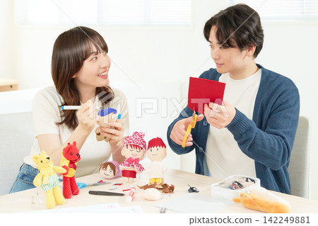 A man and woman in their 20s enjoying making stuffed animals together. A man and woman in their 20s enjoying making stuffed animals together. 142249881