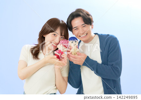 一對年輕男女面帶微笑，手裡拿著他們最喜歡的卡通人物的毛絨玩具。 142249895