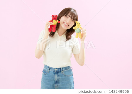 A young woman smiling while holding a stuffed animal. A young woman smiling while holding a stuffed animal. 142249906