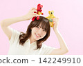 A young woman smiling while holding a stuffed animal. 142249910