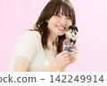 A young woman smiles, leaning her cheek against her favorite stuffed animal. 142249914