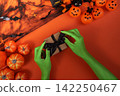 Green witch hands tying black ribbon on gift box for Halloween present concept 142250467
