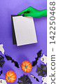Green witch hand holding blank card mockup over purple Halloween background 142250468