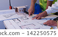 Architects and engineers pointing at blueprint floor plan during project planning meeting 142250575