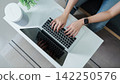 Overhead view of woman typing on laptop keyboard at white desk for work 142250576