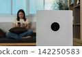 Modern white air purifier in living room with woman using smartphone in background 142250583