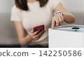 Cropped hand pressing button on smart air purifier with smartphone at home 142250586
