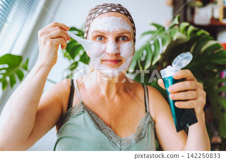 middle-aged woman cosmetic mask on face enjoys free time middle-aged woman cosmetic mask on face enjoys free time 142250833