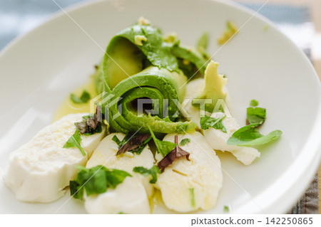 Healthy caprese salad variation with fresh avocado slices and mozzarella cheese Healthy caprese salad variation with fresh avocado slices and mozzarella cheese 142250865