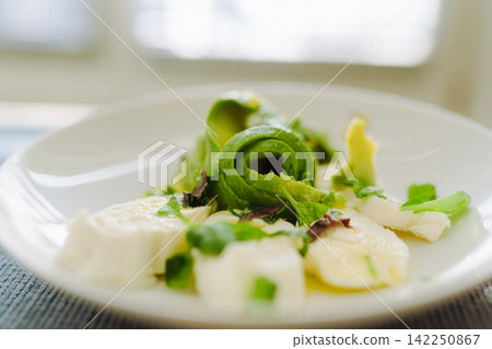 Healthy caprese salad variation with fresh avocado slices and mozzarella cheese Healthy caprese salad variation with fresh avocado slices and mozzarella cheese 142250867