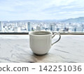 A cup by the window overlooking the cityscape 142251036