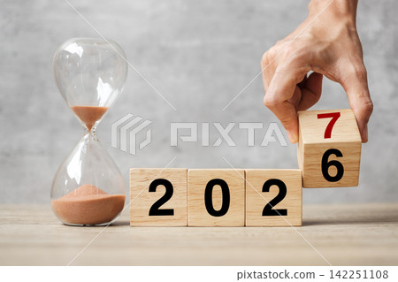 hand flipping block 2026 to 2027 text with hourglass on table. Resolution, time, plan, goal, motivation, reboot, countdown and New Year holiday concepts hand flipping block 2026 to 2027 text with hourglass on table. Resolution, time, plan, goal, motivation, reboot, countdown and New Year holiday concepts 142251108