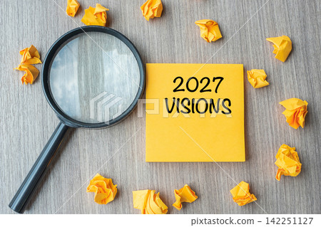 2027 VISIONS words on yellow note with crumbled paper and magnifying glass on wooden table background. New Year New Start, Idea, Strategy, and Goals concept 2027 VISIONS words on yellow note with crumbled paper and magnifying glass on wooden table background. New Year New Start, Idea, Strategy, and Goals concept 142251127
