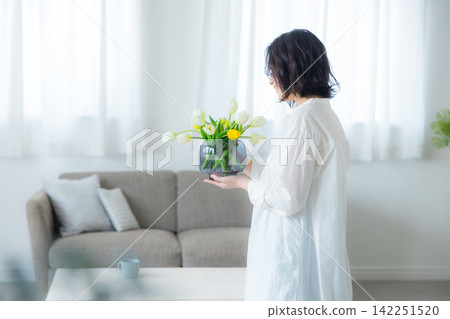 一位年輕女子在客廳拿著花瓶 142251520