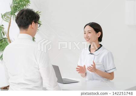 A female clinic receptionist and a male patient A female clinic receptionist and a male patient 142251748