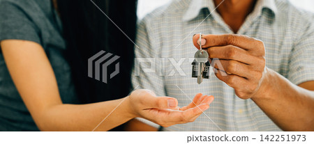 A delighted couple celebrates new homeownership displaying keys to their house A delighted couple celebrates new homeownership displaying keys to their house 142251973