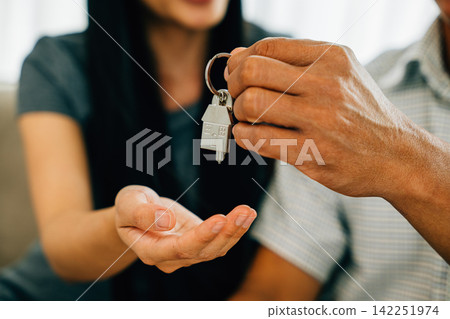 A delighted couple celebrates new homeownership displaying keys to their house A delighted couple celebrates new homeownership displaying keys to their house 142251974